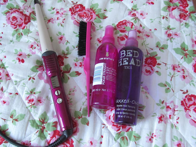 pink curling wand, pink and black backcolmbing brush, pink spray bottle, purple spray bottle