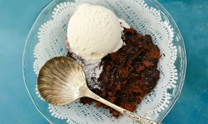 Self-saucing chocolate pudding in a glass bowl with a scoop of vanilla ice cream