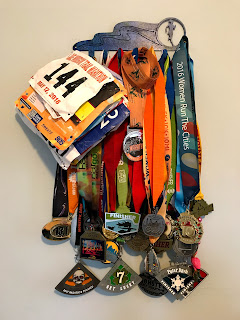 Photo of running medals and running race bibs on a medal hanger and 