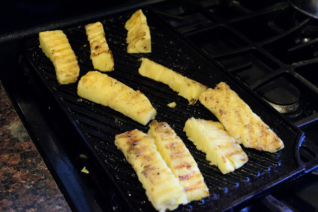 Pieces of pineapple cooking on the grill pan.