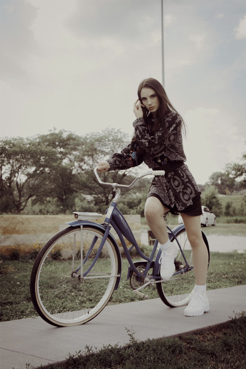 model in vintage clothing is posing on a bicycle