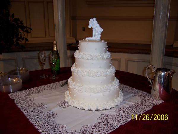 4 tier round cake covered with fondant Hand made tipped frosting roses at