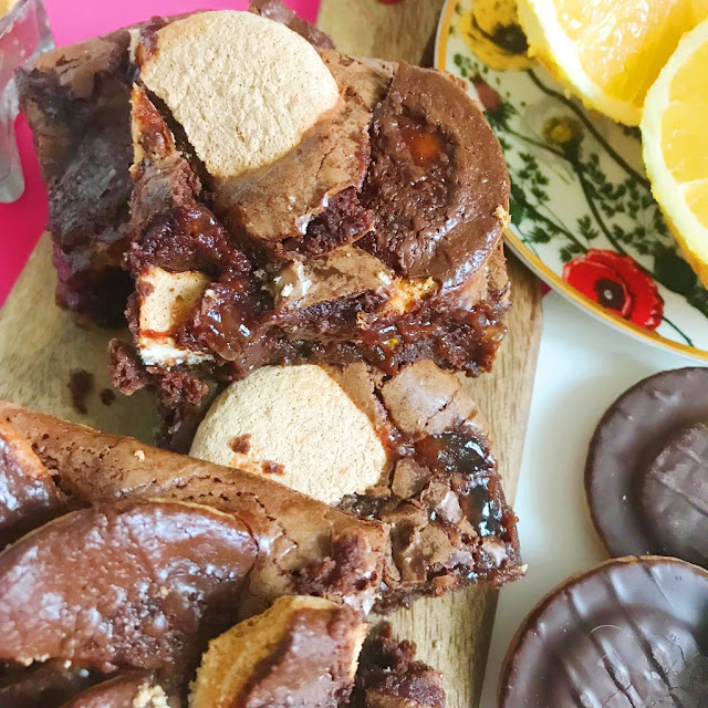 closeup of jaffa cake brownies on chopping board. Orange sliced open and jaffa cakes next to it on the right