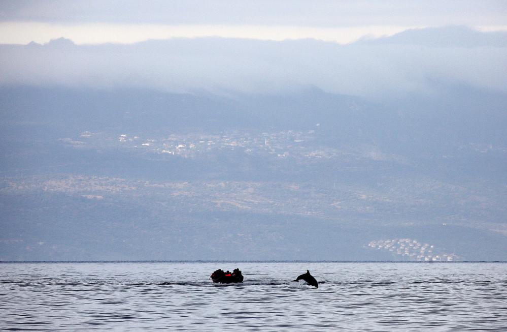 70 Of The Most Touching Photos Taken In 2015 - A dolphin jumping next to the refugees' raft