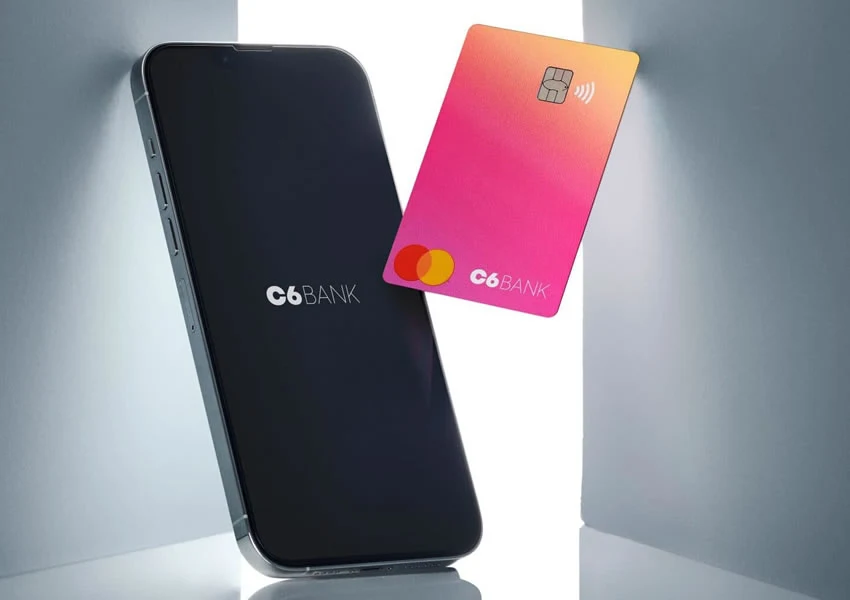 A imagem mostra um celular com o app do banco C6 Bank aberto ao lado do cartão do banco.