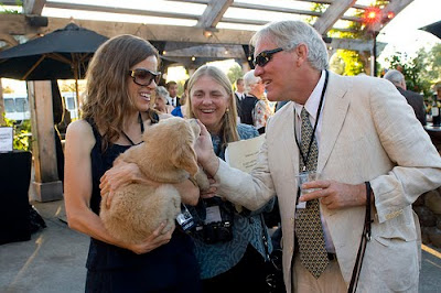 George Thompson, with his wife Margot, greet a Golden Retriever puppy held by GDB staff member Denise St. Jean. 