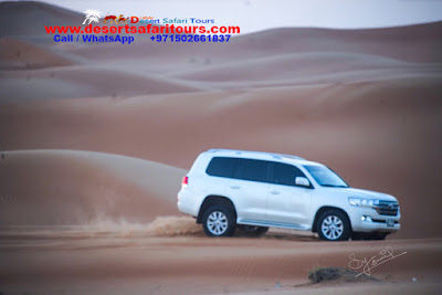 one white vehicle driving on the dunes dubai