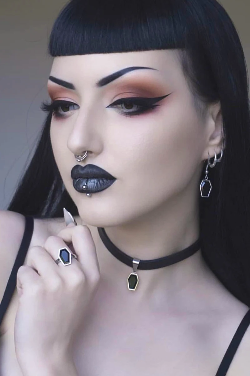 portrait of a beautiful woman with bold makeup look and baby bangs goth hair