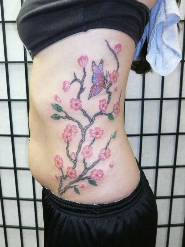 A first tattoo cherry blossoms gracing her side This freehand tattoo was
