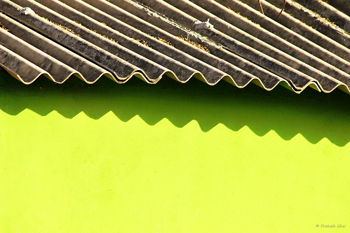 A Minimalist Photo of the green wall and wavy cement Roof of a kindergarten school in Bani Park Jaipur