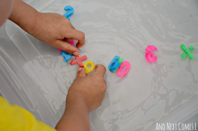 Child playing with colorful number magnets in a water