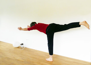 balancing pose standing on one leg arms out front and the other leg out the back forming a T