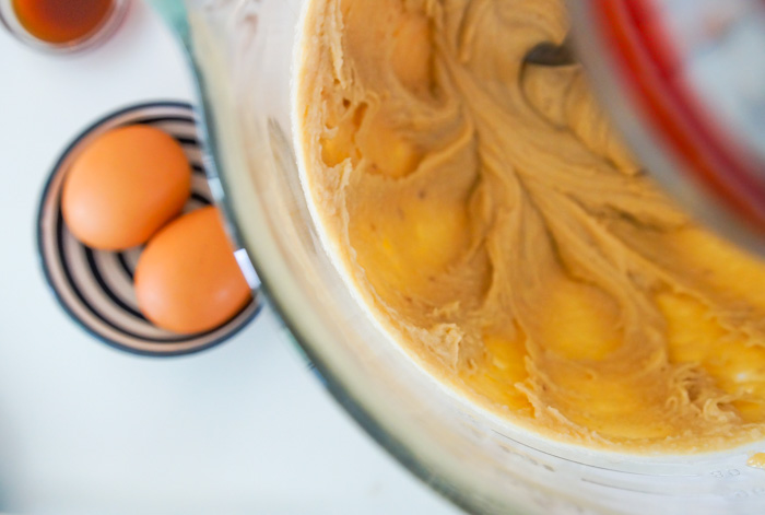 cookie dough in bowl of kitchenaid mixer. Eggs in background