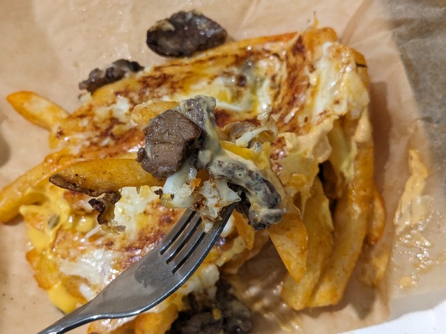 Close-up view of a forkful of Taco Bell's Grilled Cheese Nacho Fries.