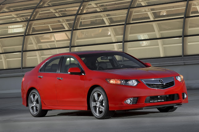 Front three-quarters view of red 2012 Acura TSX on rooftop garage in front of skylight