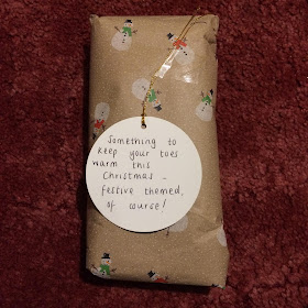 A wrapped present with a tag reading, Something to keep your toes warm this Christmas - festive themed, of course!