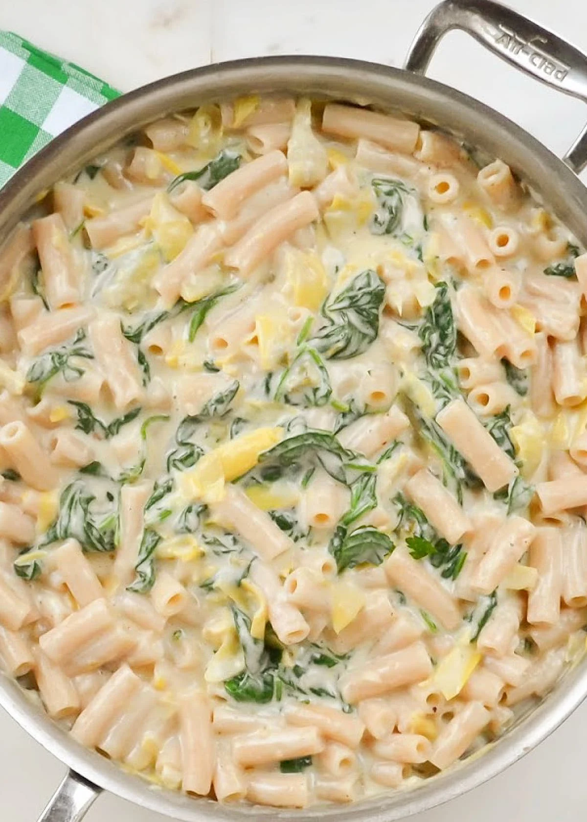 Spinach Artichoke Pasta in a stainless steel skillet.