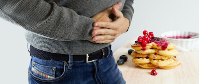 Man holding stomach after eating too much sugar