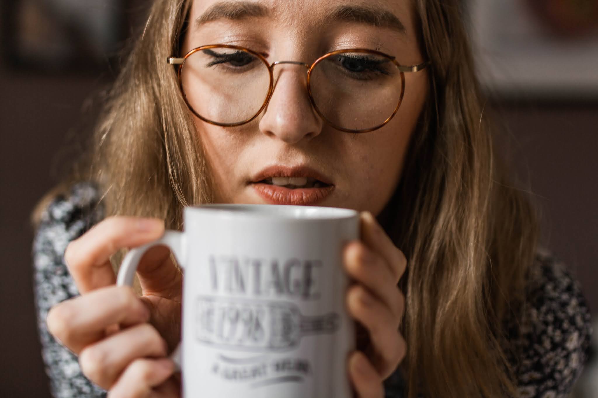 blonde girl with glasses holding white mug