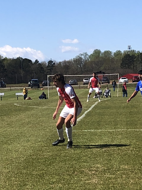 Josh kinda crouched down as an opposing player is making his way down field with the ball. Josh is getting ready to challenge the play.