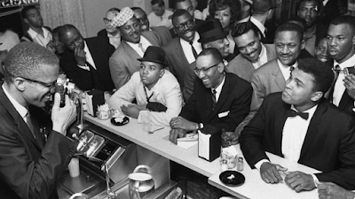 Malcolm X photographs Muhammad Ali at the victory party after Ali’s defeat of Sonny Liston, February 25, 1964. Photograph by Bob Gomel