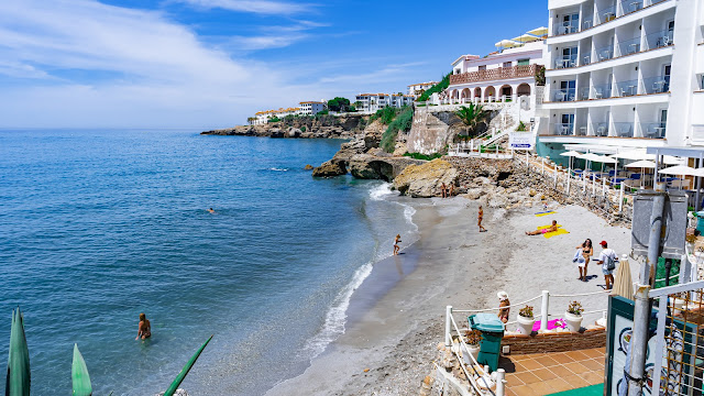 Pequeña cala con gente y edificios a su espalda.