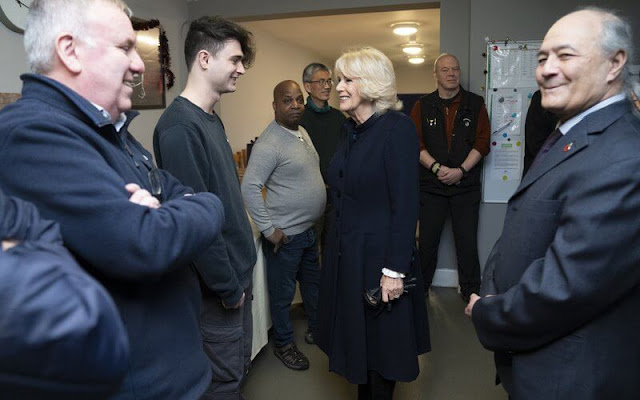 Queen Camilla wore a navy blue wool midi coat and black suede boots. The Queen visited the Emmaus boutique