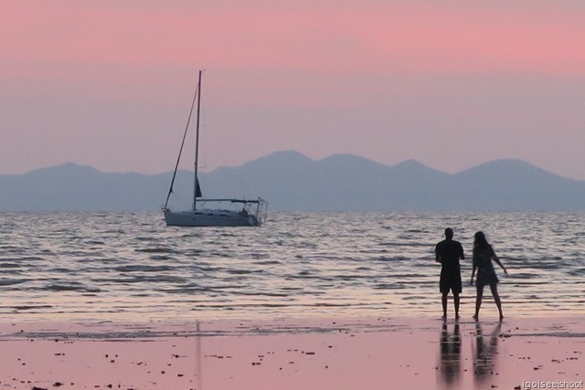 Boat and couple bathed in pink colours of twilight as seen from Nopparat Thara Beach