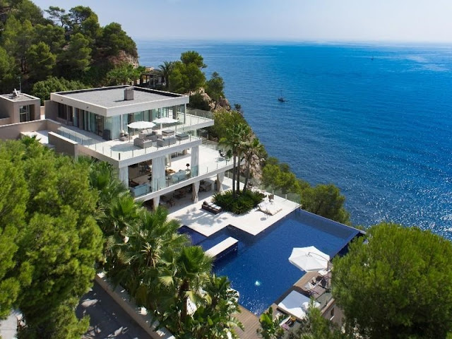 Modern dream home built on the cliff above the ocean surrounded by green vegetation