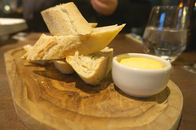 Sourdough bread and pot of butter on wooden board