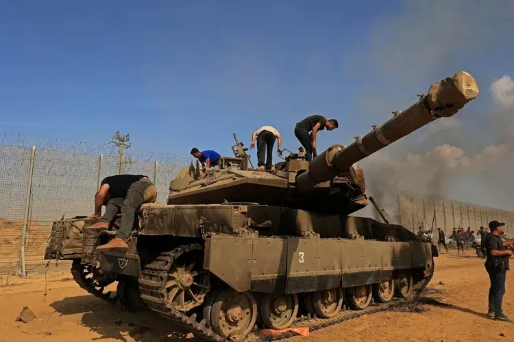 Palestinians take control of an Israeli Merkava battle tank after crossing the border fence with Israel from Khan Yunis in the southern Gaza Strip on October 7, 2023.SAID KHATIB / AFP
