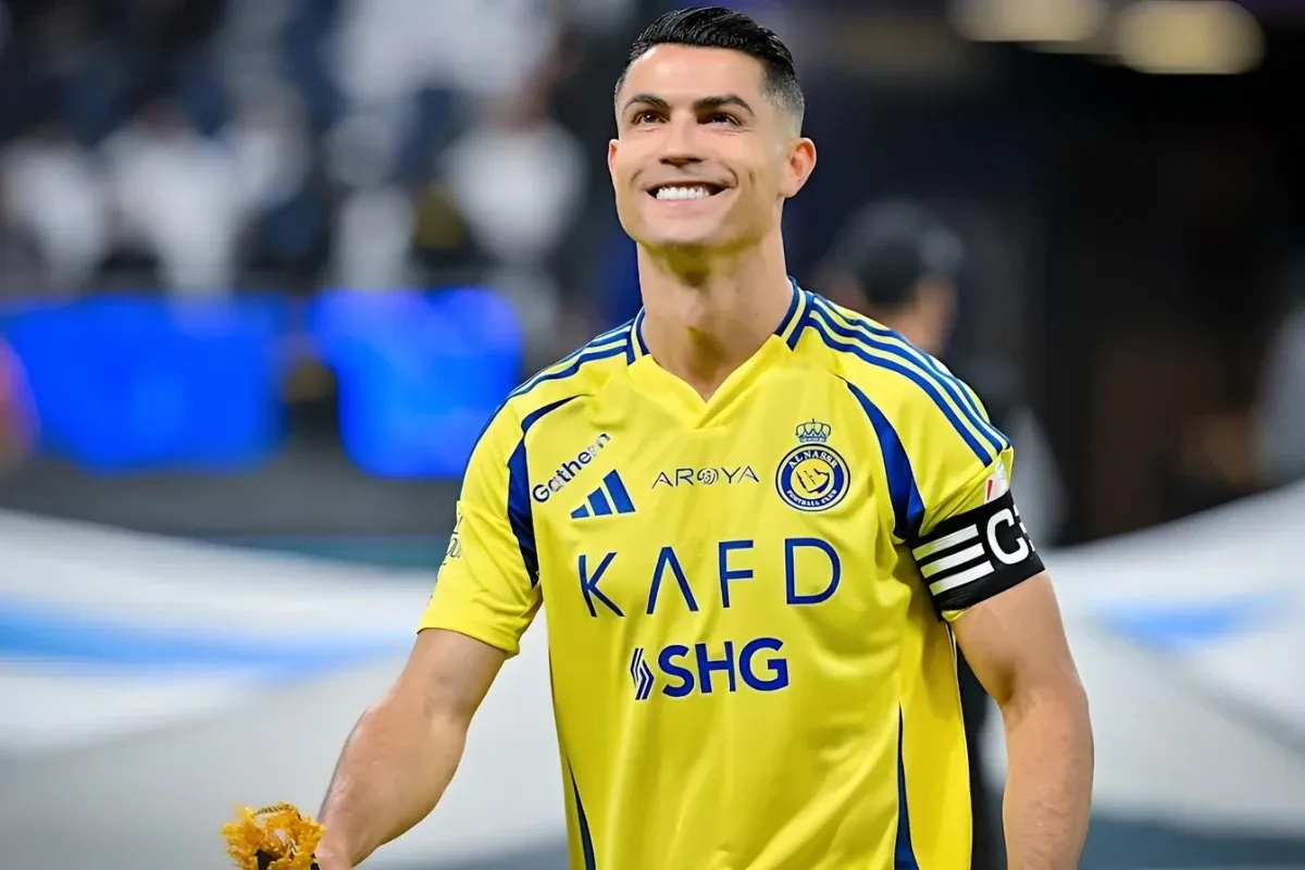 Cristiano Ronaldo Jogador de futebol comemorando usando a camisa do time, com expressão de alegria em um estádio de futebol.