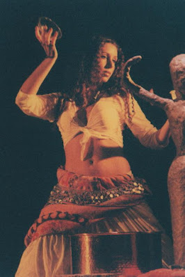 Associazione Culturale Orchestés "ARDVI SURA ANAHITA"  TEATRO TENDA PIANETA, 2003   Danza Dea Madre Nell'ambito di "Sura, o dell'ebbrezza divina". Lo spettacolo "Ardvi Sura Anahita" nasce come prosecuzione del primo "Devi - Inno alla Dea Madre", ambedue prodotti per "Off Broadway " 2003 e 2004 (Mediascena Europa), riprendendone e sviluppandone alcuni spunti particolari inerenti all' indagine sulla spiritualità femminile concepita in modo istintivo, corporeo e primordiale.  Prende quindi il titolo dal nome dell'antica divinità persiana (i cui attributi erano infatti "umida, fertile e feconda") che presiedeva alle acque, Dea celeste fonte di tutte le acque terrestri, elemento che domina sovrano nelle danze mediorientali, caratterizzate da un moto fluido, ipnotico ed arcaico. Una Dea delle Acque quindi, per una danza anticamente legata ai culti della fecondità i cui moti circolari riportano ad un vissuto arcaico e non lineare del tempo. Lo spettacolo si sviluppa in una serie di quadri che alternano canti, danze e recitazione mirando a suggerire un panorama quasi onirico della spiritualità femminile: dal piacere corporeo di un gruppo di ragazze che giocano con le gonne, all'estasi liberatoria delle danza vorticose, al rapporto con quel "velo" che tutto copre. Viene quindi utilizzato un linguaggio sincretico che mira a rivalutare la bellezza di questa antica tecnica, liberandola da forme parodistiche pseudo-orientali, se non addirittura cabarettistiche, in cui la cultura attuale sembra relegarla. Non più "movenze femminili", ma la ricerca del movimento potente, che ridia alla donna la sensazione di un femminile totale, multiforme e spiritualizzato, aldilà del confine in cui ogni cultura ha sempre cercato di rinchiudere queste "acque mutevoli".  Coreografia e regia: Marialuisa Sales;  Interpreti:  Daniela Cipriani; Carlotta Facchini; Marialuisa Sales; Paola Stella;  Giovanna Leva Joglekar (per il brano di Fusion);  Attrici-Danzatrici:  Camilla Triolo; Giovanna Genovese;  Testi: liriche dei poeti classici Rumi, Jami;  Decorazioni: Paola D'Alberti Repliche per  "Terzo Festival di Danza Multietnica" di Roma (2004);  "San Lorenzo, Arte in Movimento" (2004) (CLICCARE SULLA PRIMA FOTO PER APRIRE LA VISUALIZZAZIONE)