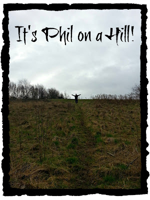 Man standing at top of hill, arms outstretched