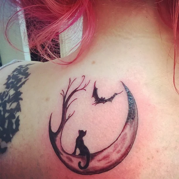 peliroja con tatuaje en el omoplato de un gato y la luna