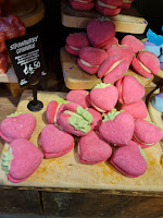 A zoomed in photo of a bunch of strawberry shaped light pink bubble bar with green accents with a light pink buttercream in the middle with a black rectangular card with strawberry crumble bubbleroon un white font on a bright background
