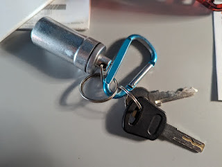 keys and pill bottle attached to carabiner on a desk surface