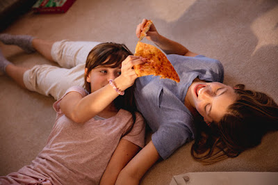 mom and daughter sharing pizza on the floor