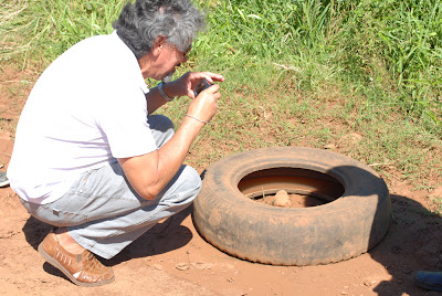 Ramão está agachado de frente para o pneu, ele está apontando a câmera na direção do objeto.