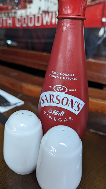 Sarson's malt vinegar bottle against salt and pepper pots on a table