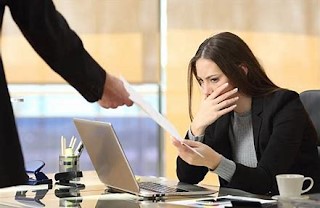 Woman at work with hand over mouth receiving bad notice from boss