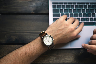 person with wristwatch working on a MacBook