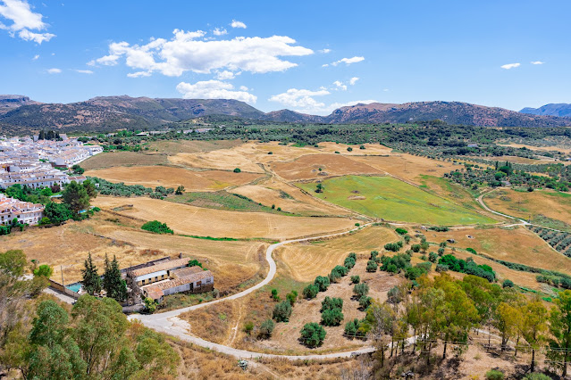 Paisaje de un gran valle con cultivos y vegetación, y las montañas al fondo, un día soleado con cielo azul.