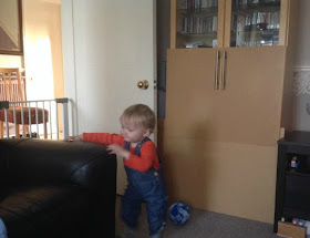 toddler in room with gate across doorway and board at glass furniture