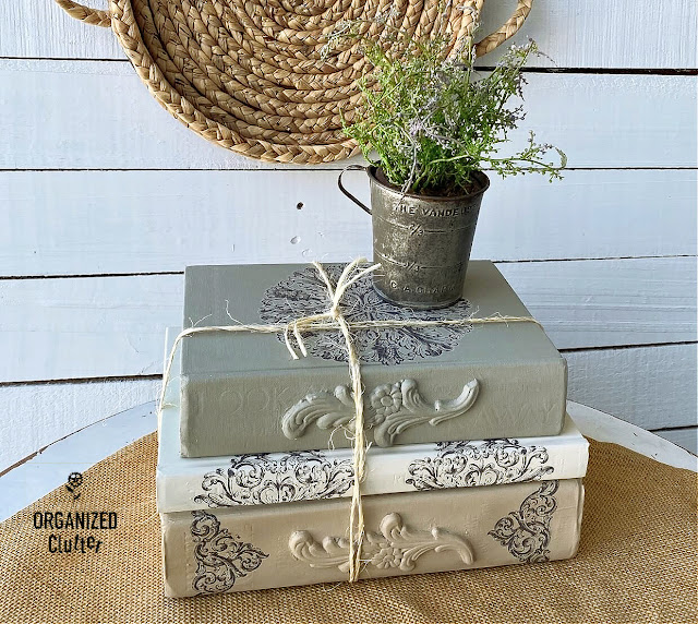 Photo of a DIY decorative book stack with wooden appliques, rub on transfers and Dixie Belle Chalk Paint.