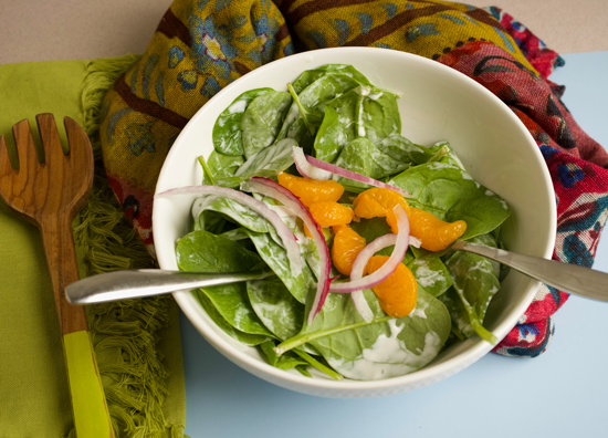 Bowl of spinach salad with mandarin oranges and red onions