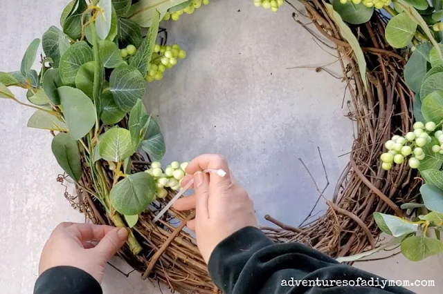 Using zip ties to secure the greenery wreath to the grapevine wreath.