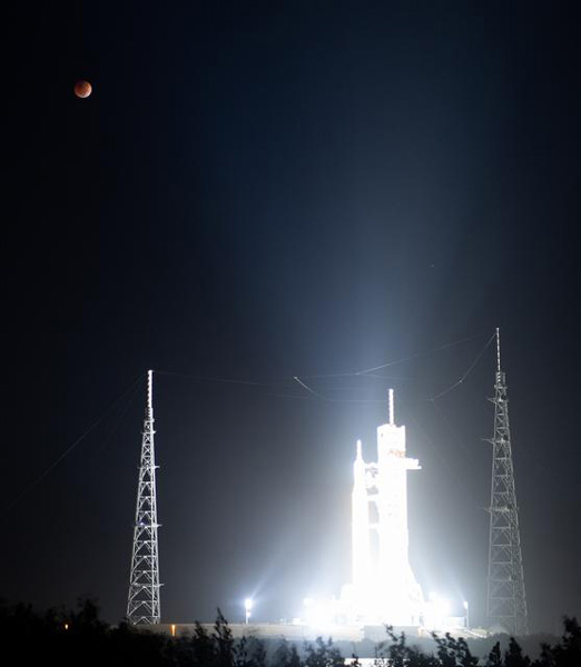 NASA's Space Launch System rocket stands tall at Kennedy Space Center's Pad 39B in Florida as a total lunar eclipse looms high above it...on November 8, 2022.