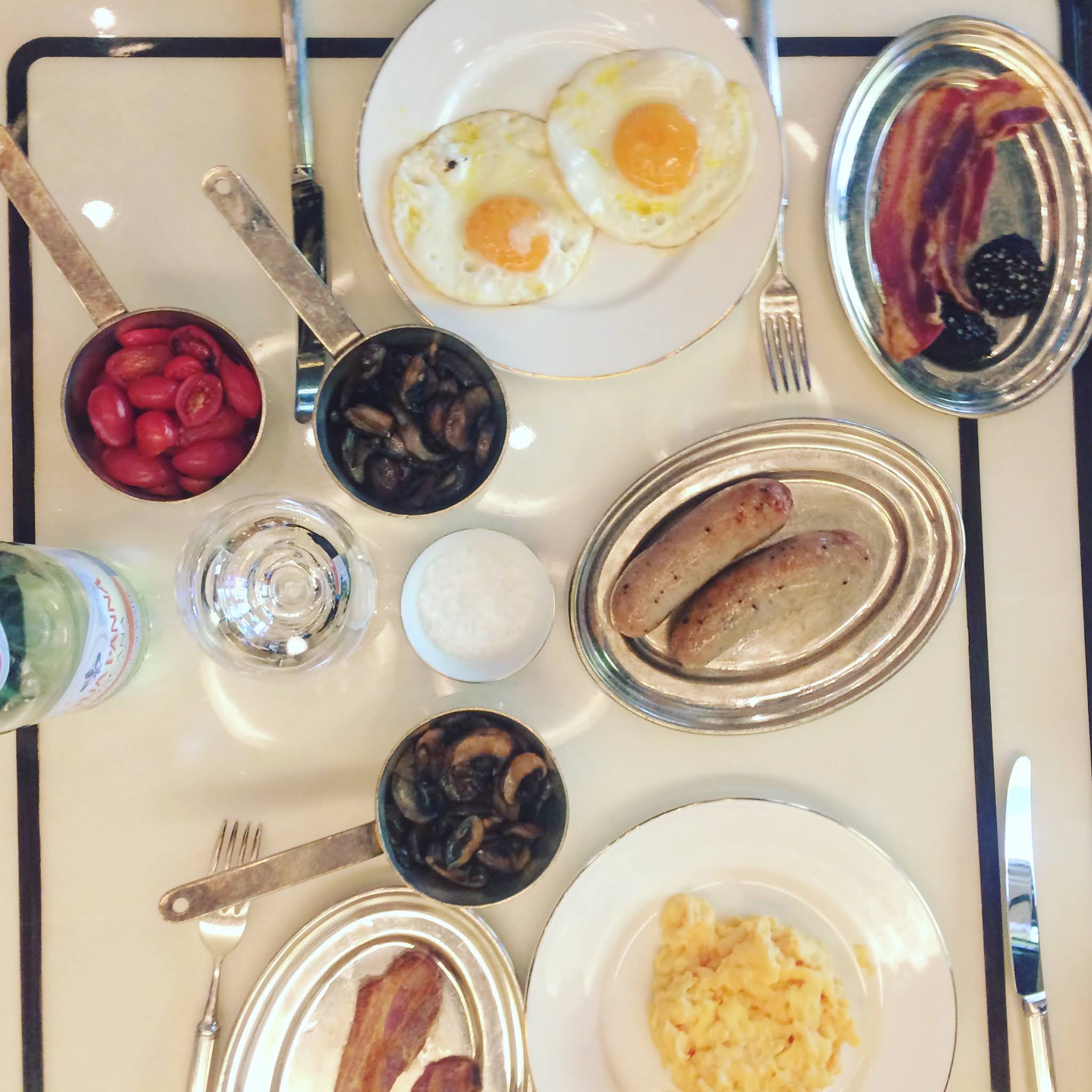 A flat lay of fried eggs, black pudding, sausages, mushrooms and tomatoes at luxury london breakfast spot Isabel in Mayfair