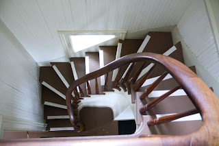 Looking down into a spiral staircase that is rectangular to match the narrow rectangular walls that border it